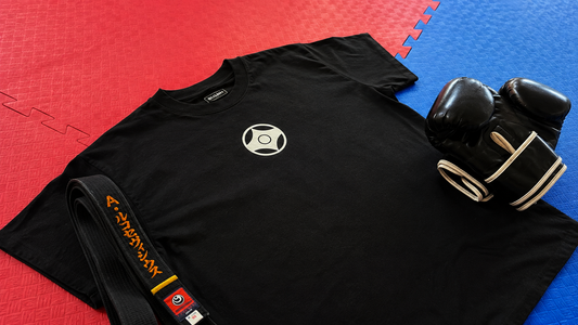 Black BUSHIN Kyokushin T-shirt with white kanji laid on red and blue karate tatami mats