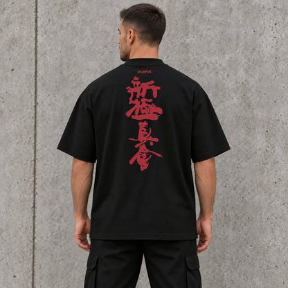 Back view of a male model wearing a black BUSHIN oversized T-shirt with vertical crimson Shinkyokushin kanji and BUSHIN branding.