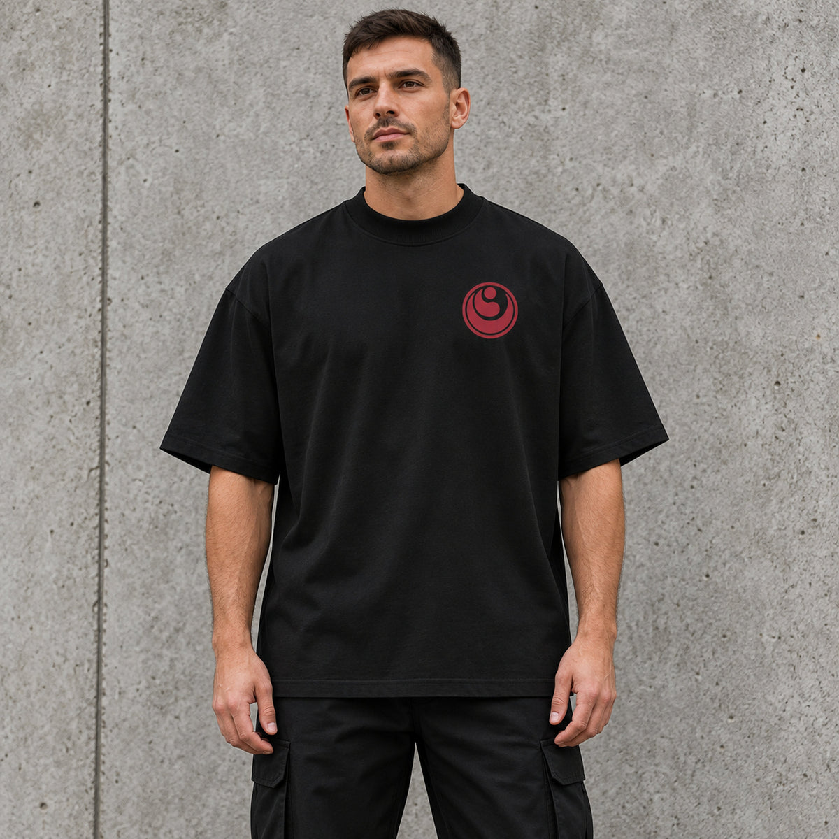 Male model wearing a black BUSHIN oversized high-neck T-shirt with a crimson Shinkyokushin emblem on the left chest.