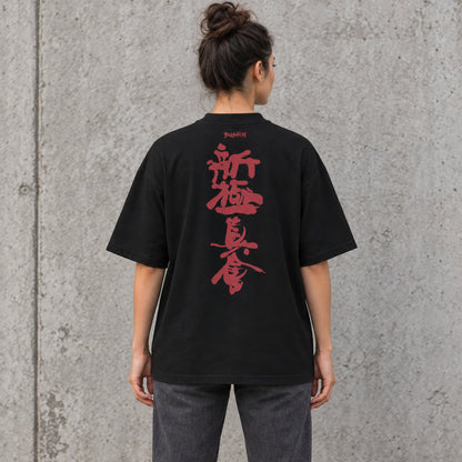 Back view of a female model wearing a black BUSHIN oversized T-shirt with crimson Shinkyokushin kanji against a grey concrete wall.