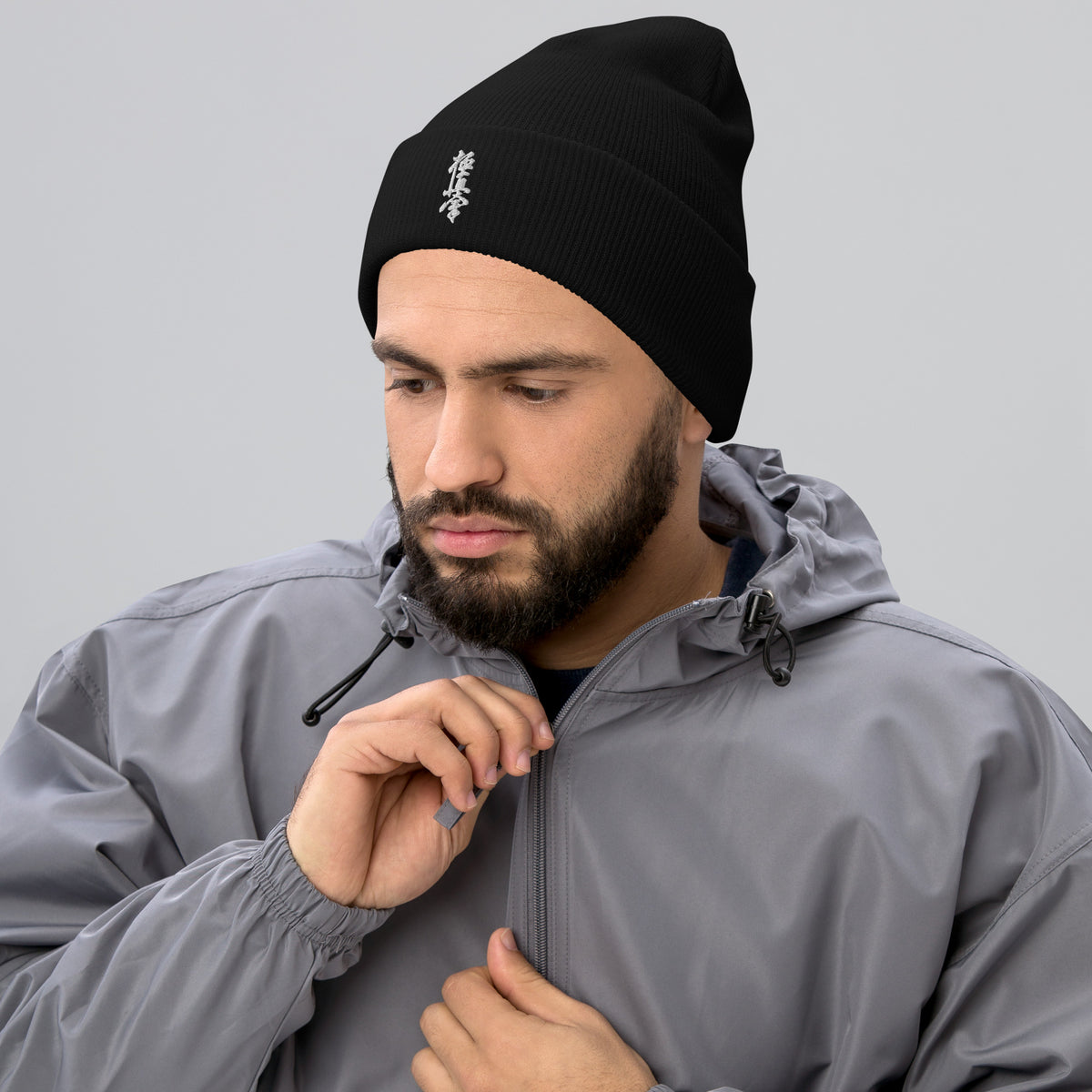 Man wearing a black Kyokushin kanji beanie with a grey jacket.