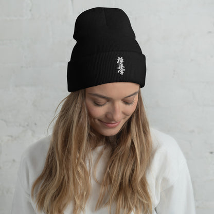 Woman wearing a black Kyokushin kanji beanie with a white top.