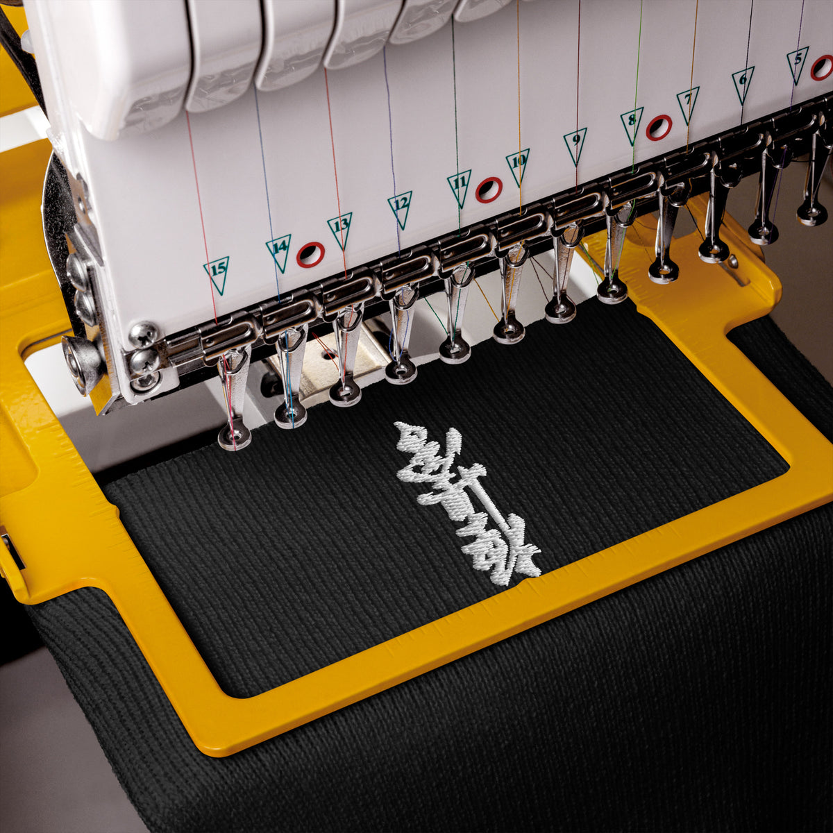 Close-up mockup of white Kyokushin kanji embroidery on a black beanie beneath an embroidery machine.