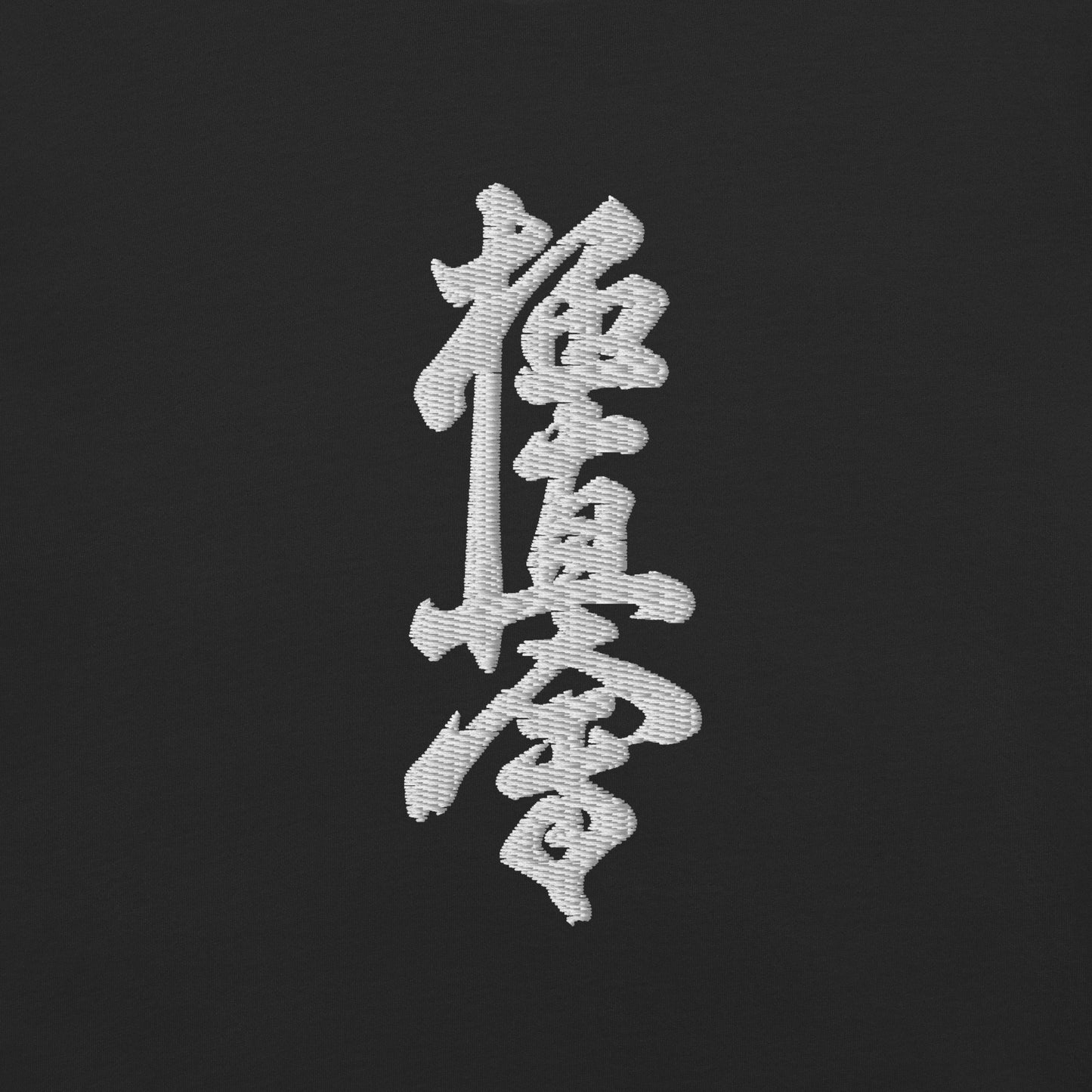 A close-up of a black fabric surface featuring a large white embroidered Japanese calligraphy character in the center.