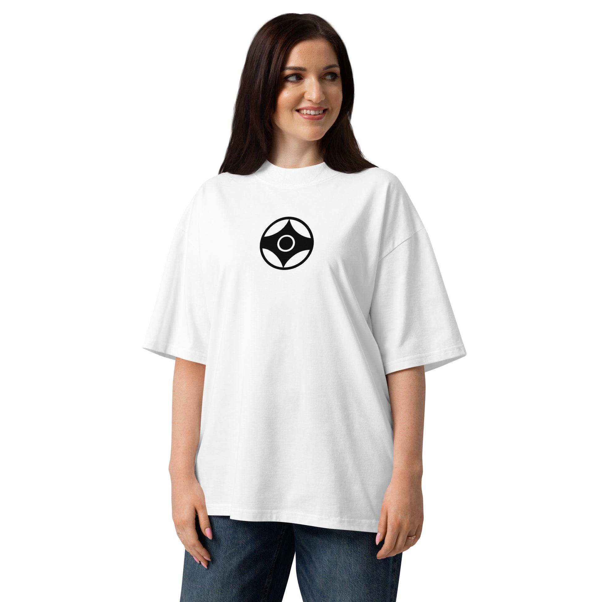 A woman wearing an oversized white t-shirt with a black circular kanku logo on the chest, paired with blue jeans, against a plain white background.