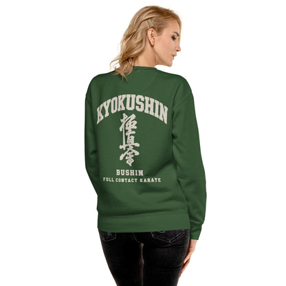 A woman shown from the back wearing a dark green crewneck sweatshirt with a large white graphic print on the back reading 'KYOKUSHIN BUSHIN FULL CONTACT KARATE' with Japanese characters. She is also wearing black jeans, set against a plain white background.
